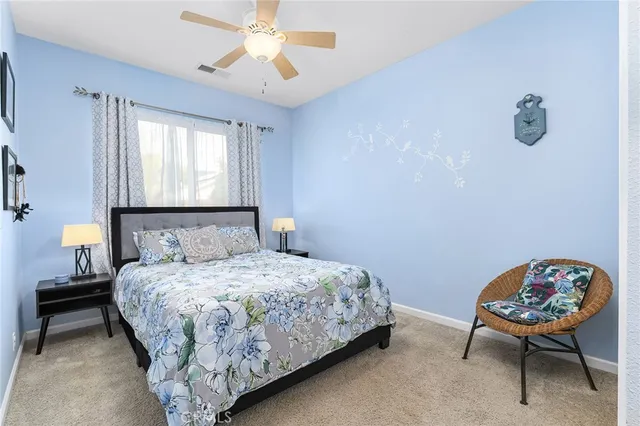 a bedroom with a bed a chair and a lamp on a dresser