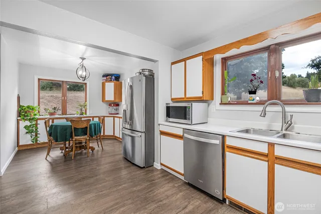 a kitchen with stainless steel appliances granite countertop a refrigerator a sink a stove and white cabinets with wooden floor