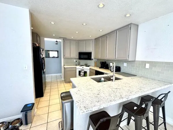 a kitchen with kitchen island granite countertop a table chairs microwave and sink
