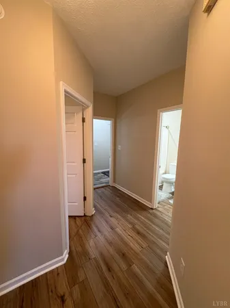 a view of an empty room with wooden floor and a ceiling fan