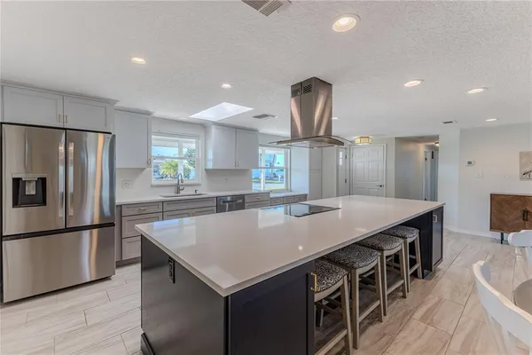 a kitchen with stainless steel appliances a sink a stove a refrigerator cabinets and wooden floor