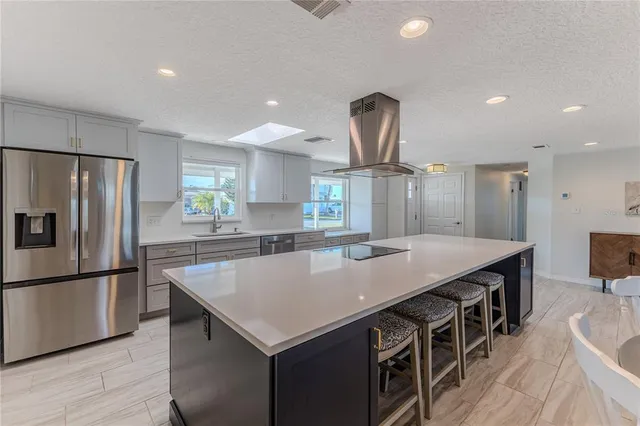 a kitchen with stainless steel appliances a sink a stove a refrigerator cabinets and wooden floor