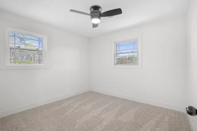 an empty room with a window and a ceiling fan