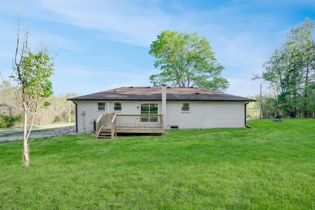 a view of a big house with a big yard and large trees