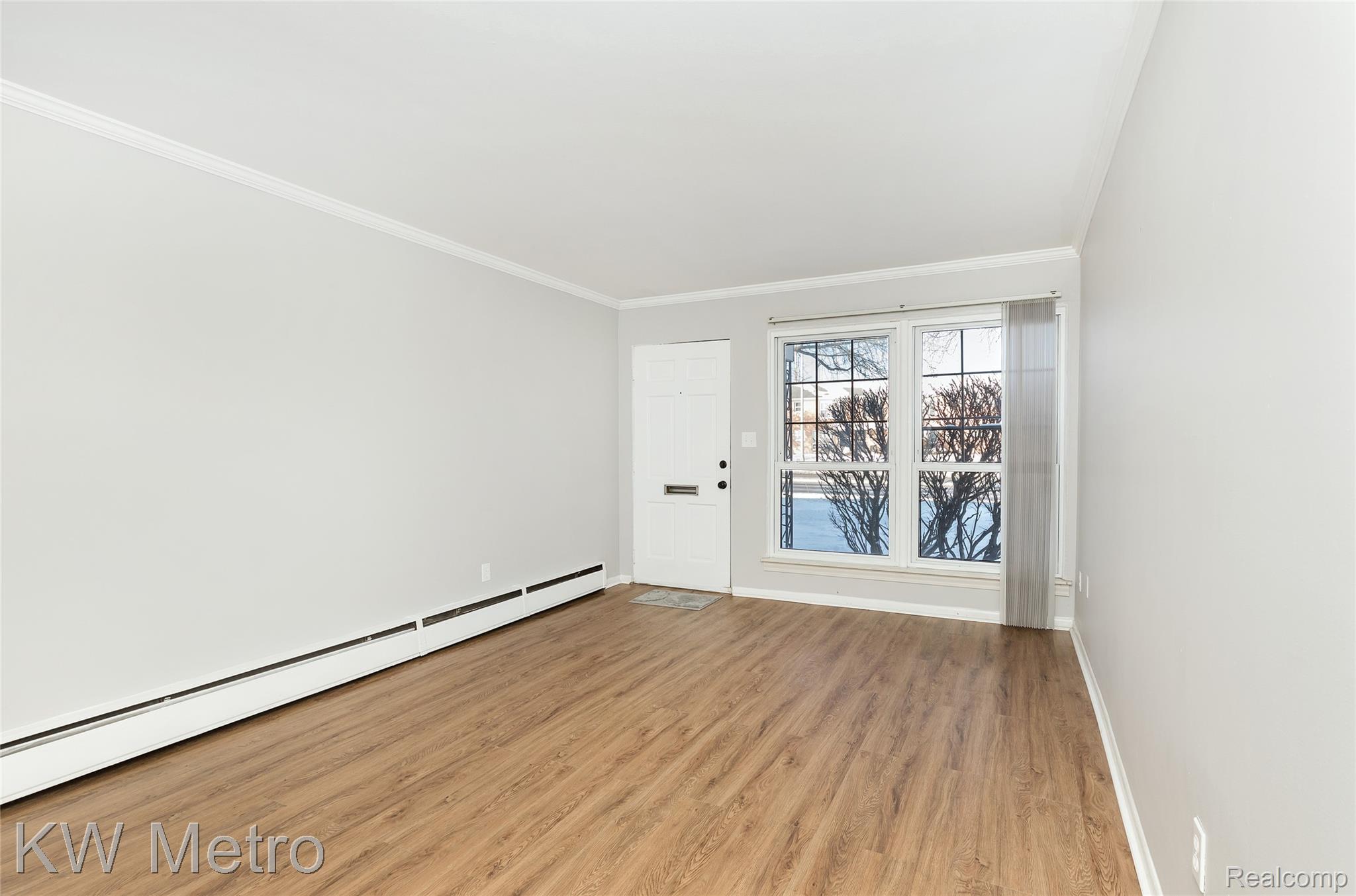 2817 West 13 Mile Road Royal Oak, MI 48073 - Photo 5 of 21 Spare room featuring baseboard heating, crown molding, and light wood-style flooring