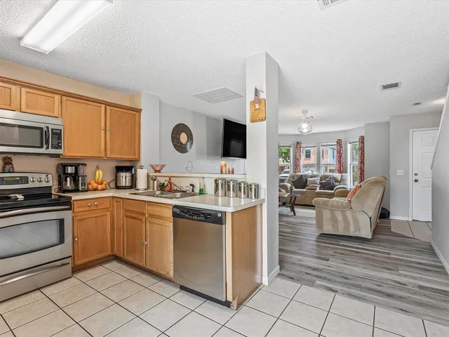 a kitchen with stainless steel appliances granite countertop a stove top oven a sink dishwasher and white cabinets with wooden floor