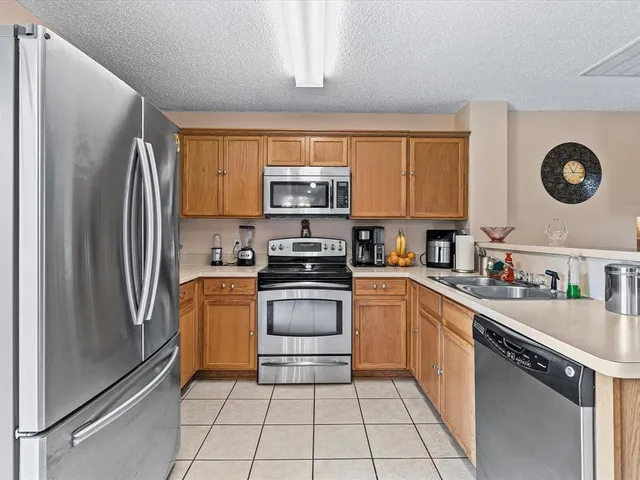 a kitchen with granite countertop a refrigerator stove top oven and sink
