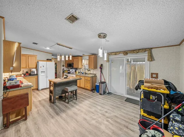 a kitchen with a refrigerator a stove a sink dishwasher and wooden cabinets with wooden floor