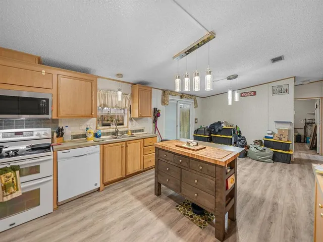 a kitchen with stainless steel appliances granite countertop a stove top oven a sink dishwasher and cabinets with wooden floor