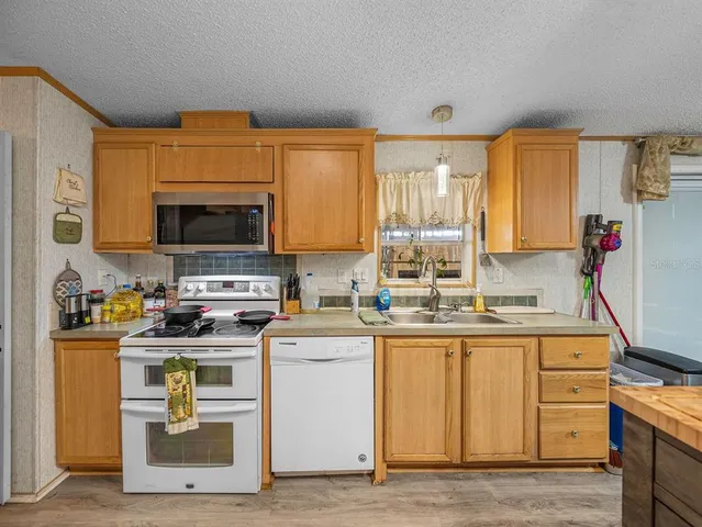 a kitchen with stainless steel appliances sink stove refrigerator and cabinets
