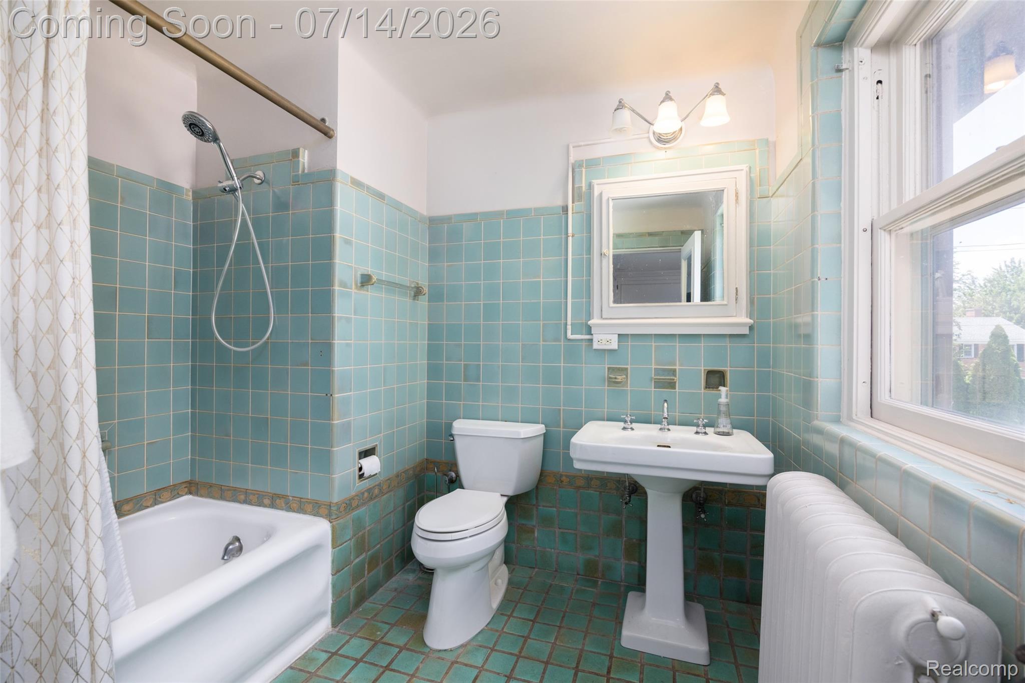 189 Cloverly Road Grosse Pointe, MI 48236 - Photo 54 of 96 Bathroom featuring a pedestal sink, white toilet, and tub with shower, all surrounded by light blue tile walls