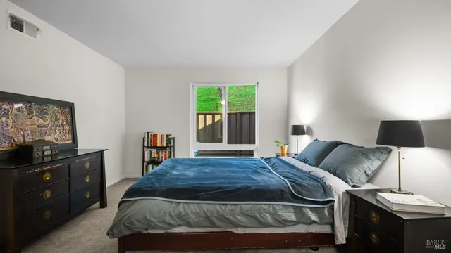 a bedroom with a bed and a flat tv screen on dresser