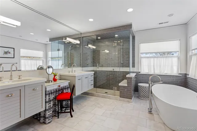 a bathroom with a tub a sink double vanity and a large window