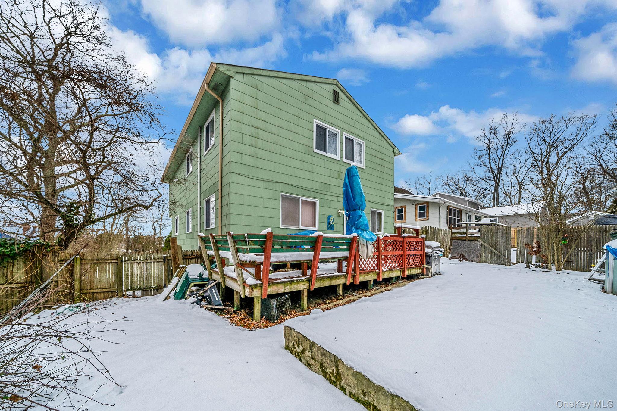 244 Lakeside Trail Ridge, NY 11961 - Photo 11 of 36 Snow covered house featuring a fenced backyard and a wooden deck