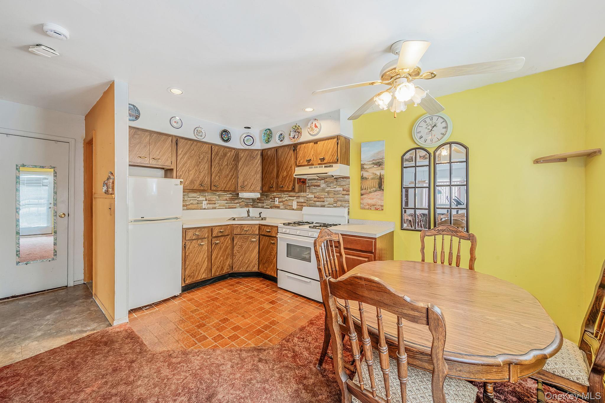244 Lakeside Trail Ridge, NY 11961 - Photo 17 of 36 Kitchen featuring white appliances, light countertops, healthy amount of natural light, brown cabinetry, and recessed lighting