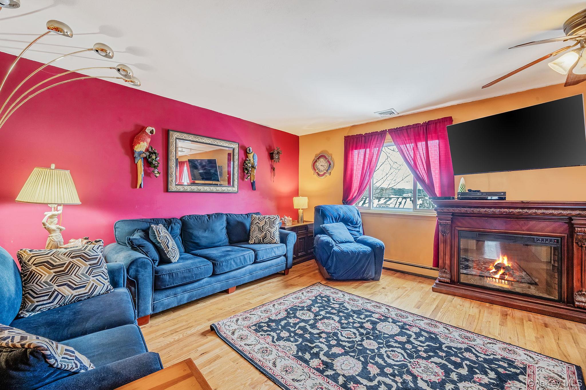 244 Lakeside Trail Ridge, NY 11961 - Photo 21 of 36 Living room with a glass covered fireplace, wood finished floors, a baseboard radiator, and ceiling fan