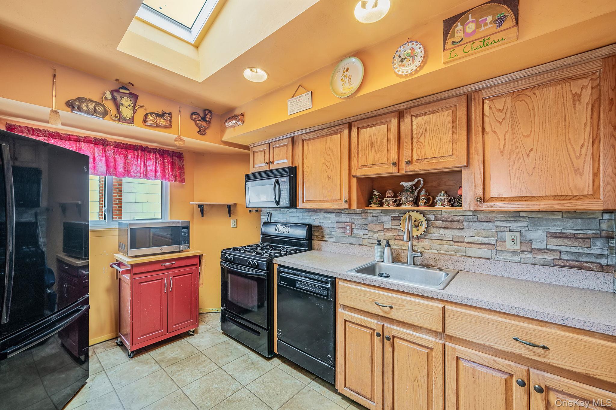 244 Lakeside Trail Ridge, NY 11961 - Photo 26 of 36 Kitchen with black appliances, a skylight, light countertops, open shelves, and light tile patterned flooring