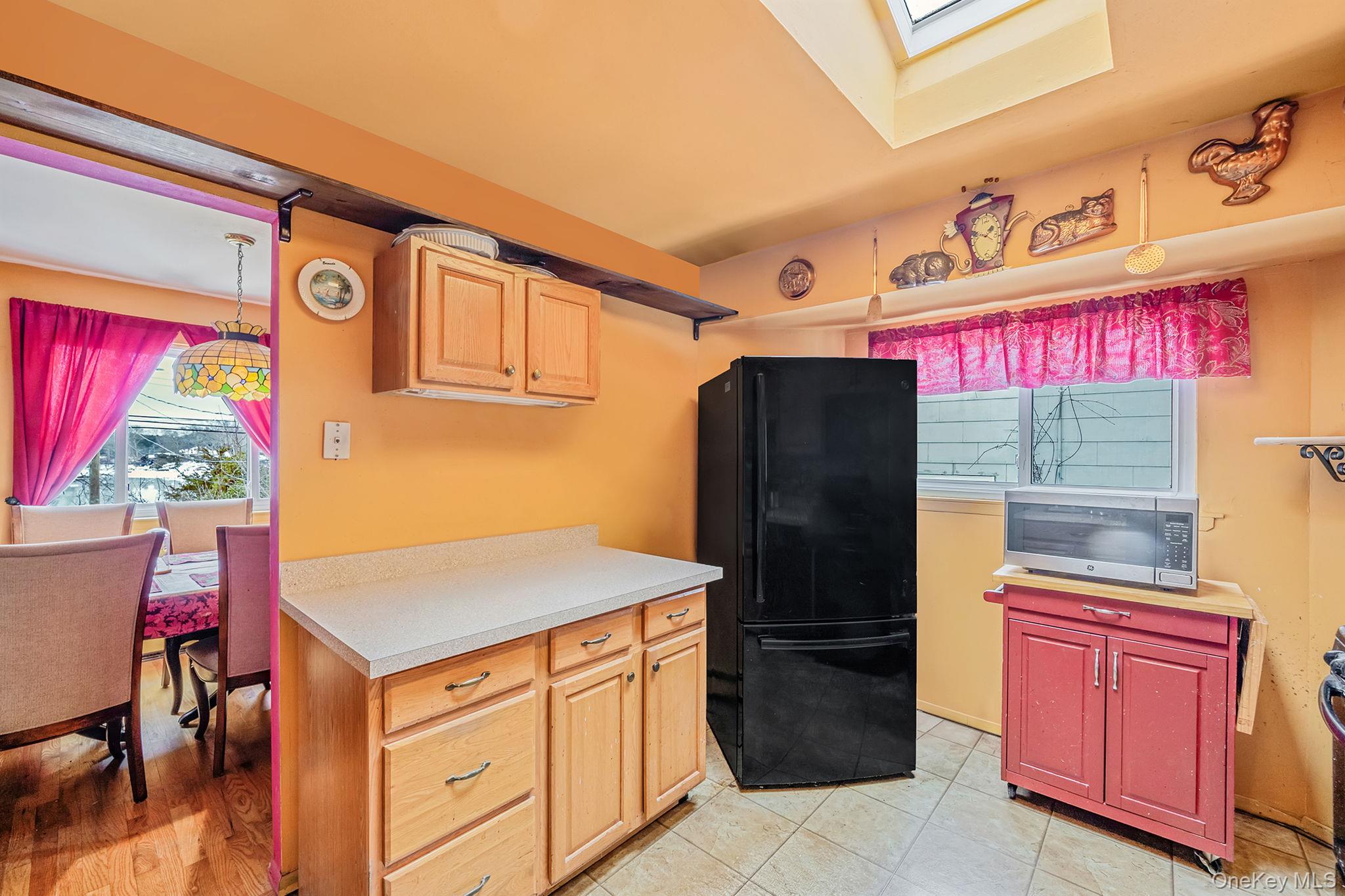 244 Lakeside Trail Ridge, NY 11961 - Photo 27 of 36 Kitchen featuring freestanding refrigerator, light countertops, stainless steel microwave, a skylight, and pendant lighting