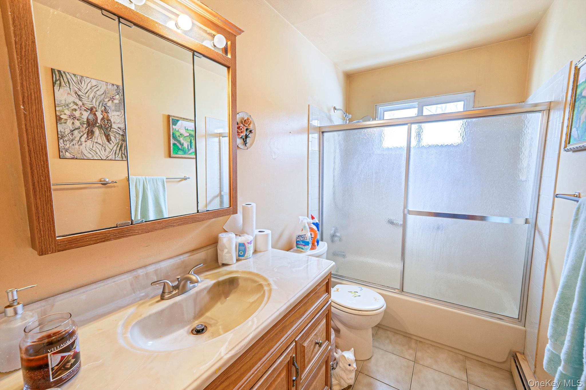 244 Lakeside Trail Ridge, NY 11961 - Photo 30 of 36 Bathroom featuring vanity, combined bath / shower with glass door, a baseboard radiator, and light tile patterned floors