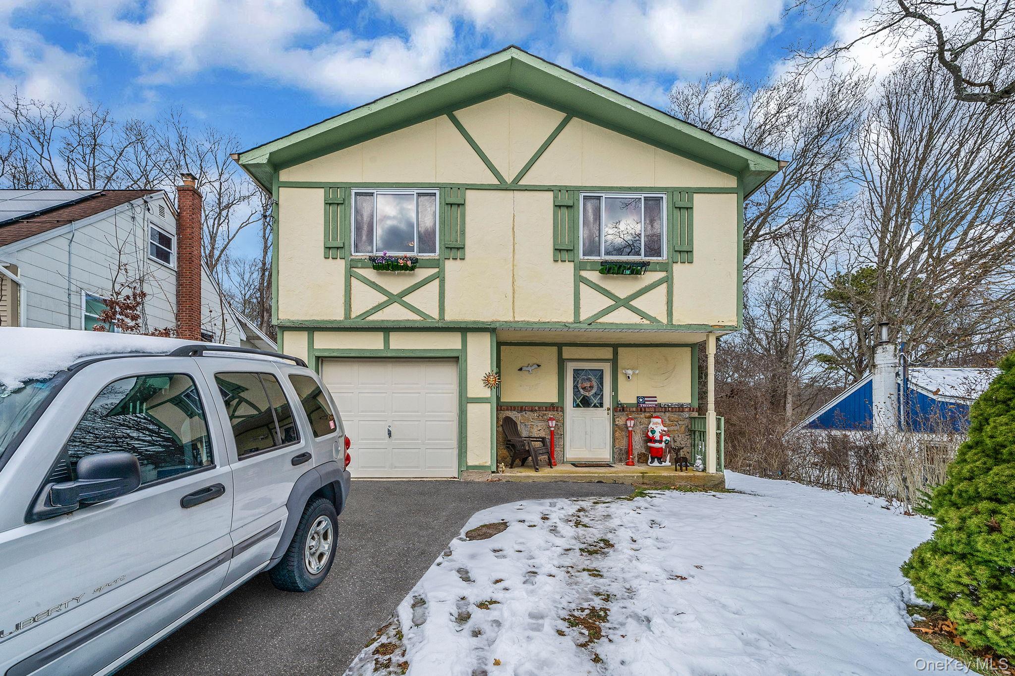 244 Lakeside Trail Ridge, NY 11961 - Photo 7 of 36 Tudor house featuring stucco siding, an attached garage, and a porch