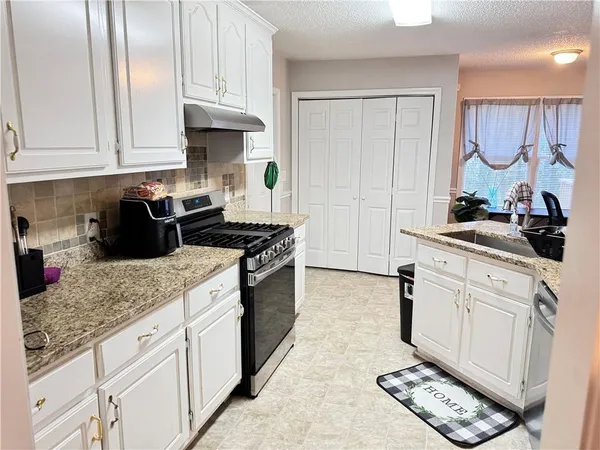 a kitchen with granite countertop a sink stove and cabinets