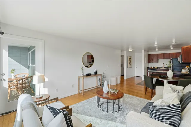 a living room with furniture kitchen view and a wooden floor