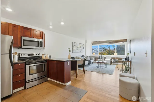 a living room with stainless steel appliances furniture and a view of kitchen