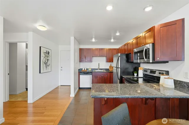 a kitchen with granite countertop kitchen island stainless steel appliances a sink a stove top oven a counter space and cabinets