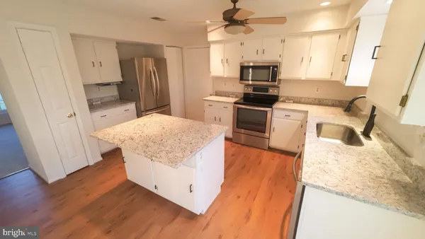 a kitchen with granite countertop a refrigerator a sink a stove a microwave and island