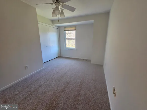 an empty room with a chandelier fan and windows