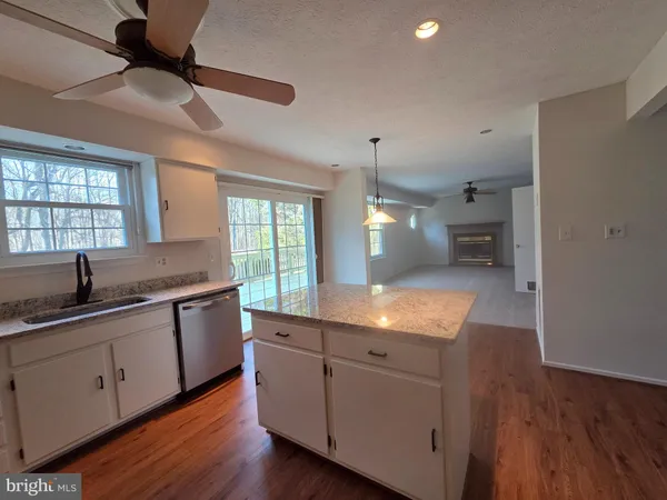 a kitchen with granite countertop a sink a counter space appliances and cabinets