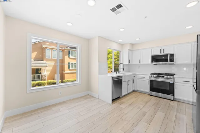 a kitchen with stainless steel appliances granite countertop a stove a sink dishwasher a refrigerator and a microwave oven with wooden floor