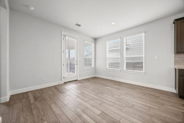 a view of an empty room with wooden floor and windows