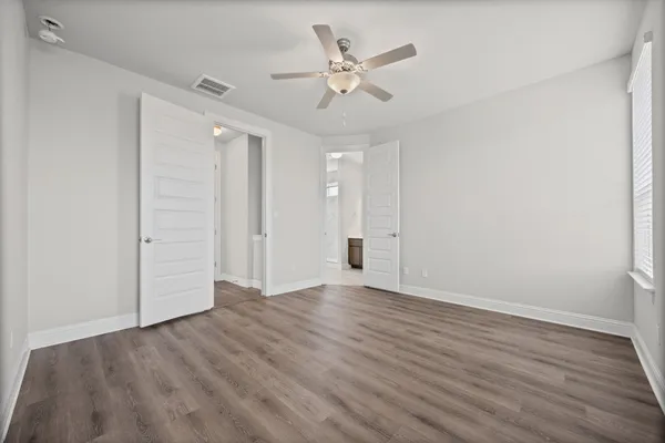 an empty room with wooden floor and ceiling fan