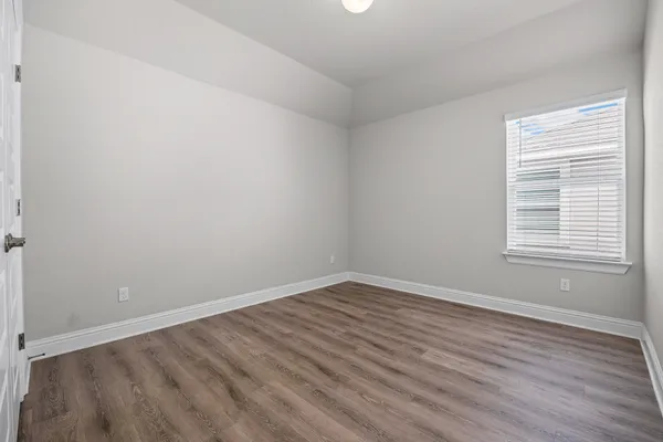 an empty room with wooden floor and windows