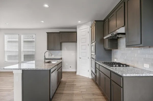 a kitchen with stainless steel appliances granite countertop a stove a sink and a refrigerator