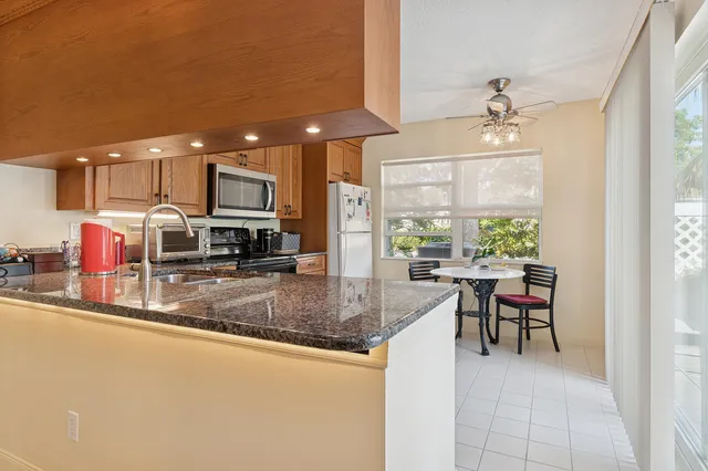 a kitchen with stainless steel appliances granite countertop dining table chairs and a refrigerator