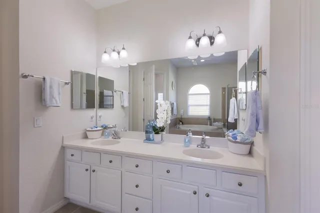 a bathroom with double vanity sinks a vanity a lamp and a mirror