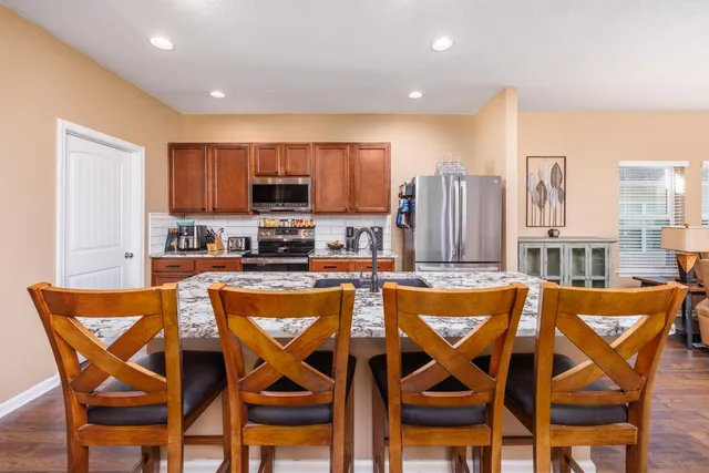 a kitchen with stainless steel appliances granite countertop a refrigerator a stove top oven a sink dishwasher and white cabinets with wooden floor