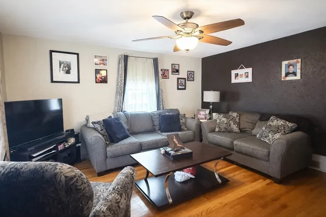 a living room with furniture a ceiling fan and a flat screen tv