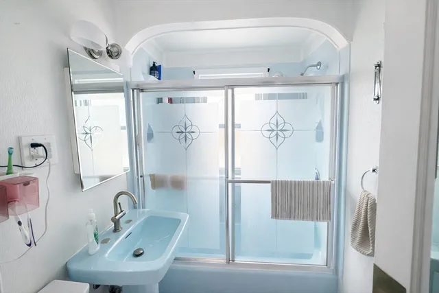 a bathroom with a sink a glass door shower and a mirror