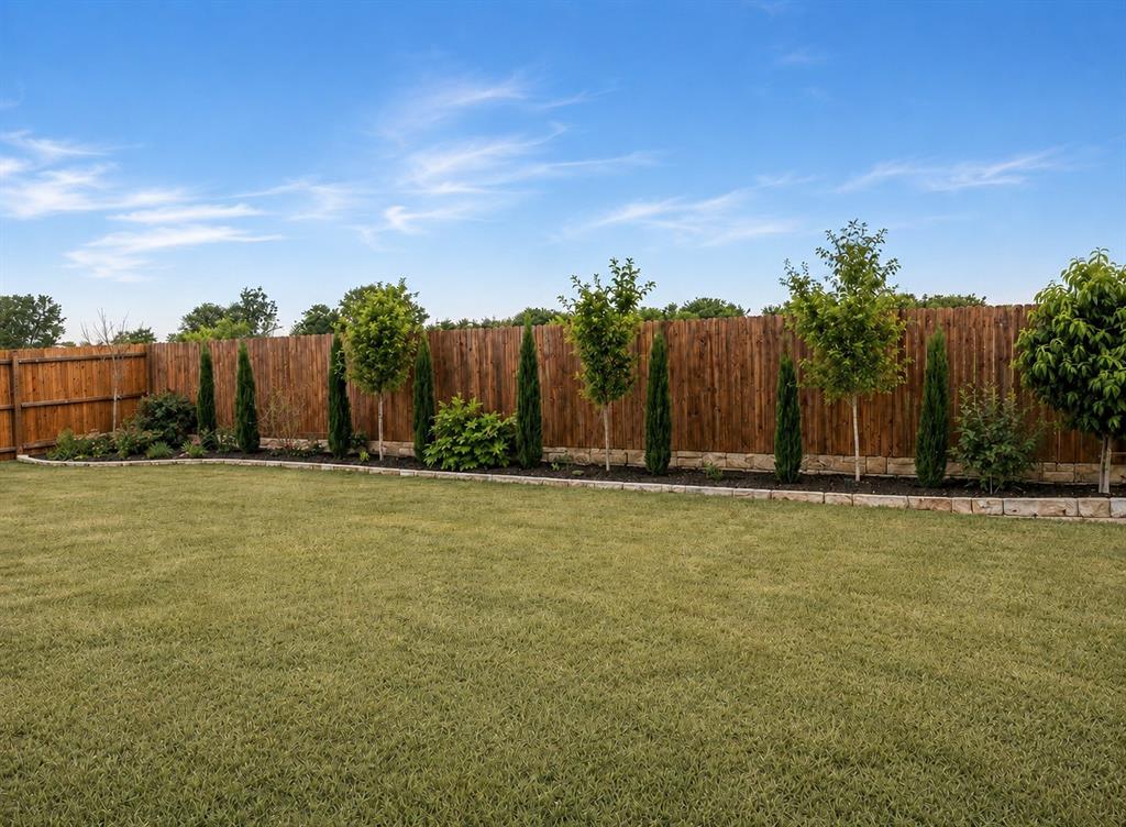 4600 Fringetree Way Crowley, TX 76036 - Photo 31 of 40 Expansive backyard featuring a lush lawn, wood privacy fencing, and a landscaped bed with diverse plantings