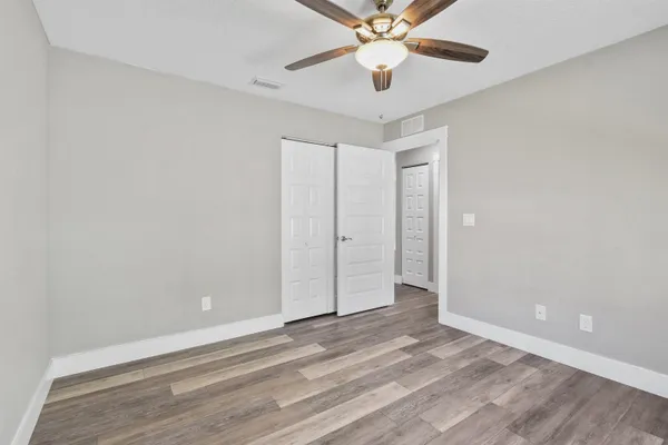 an empty room with closet and a ceiling fan