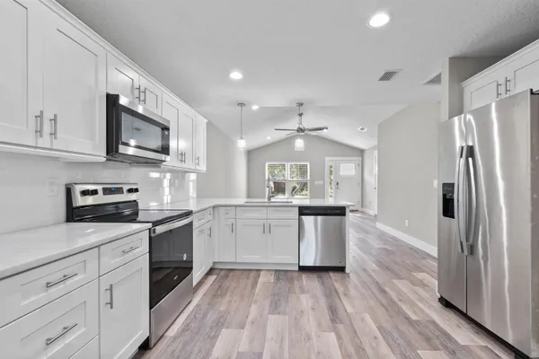 a large kitchen with cabinets wooden floor and stainless steel appliances