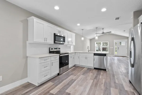 a kitchen with granite countertop a stove top oven a sink dishwasher and a refrigerator with wooden floor