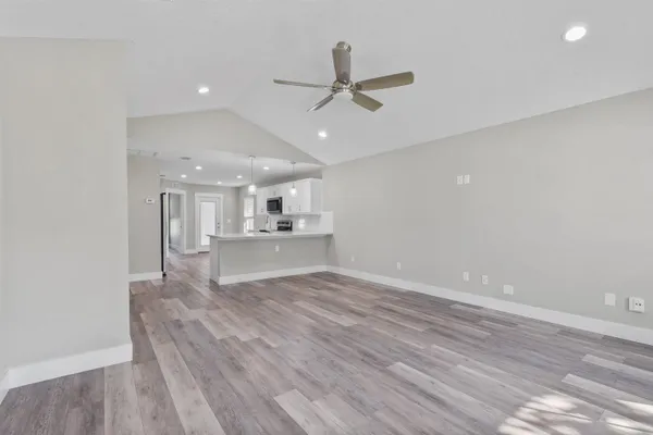 a view of kitchen and empty room with wooden floor and windows