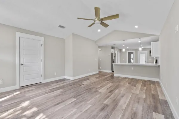 a view of a livingroom with a ceiling fan wooden floor and a ceiling fan