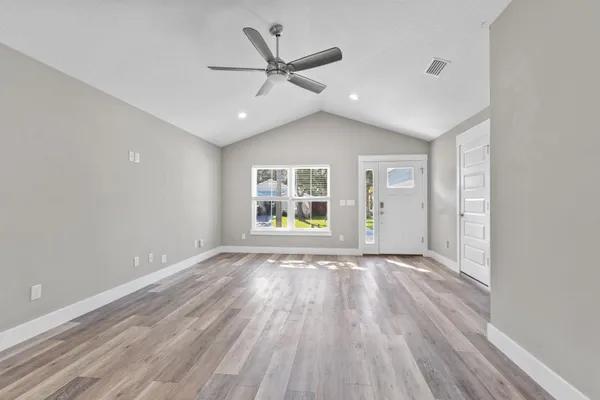 a view of an empty room with a window and wooden floor