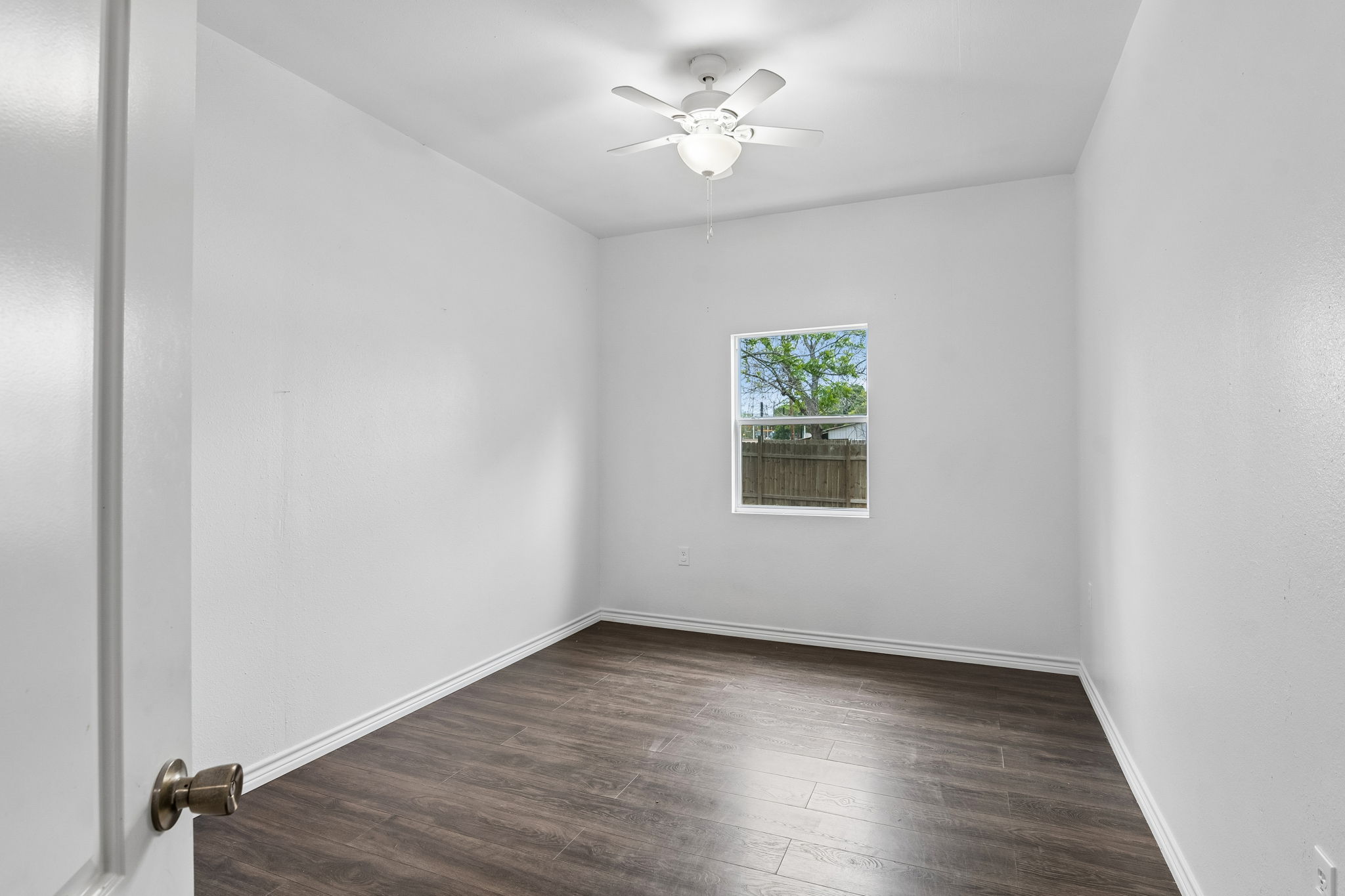 810 Lamar Street Luling, TX 78648 - Photo 18 of 21 an empty room with wooden floor chandelier fan and windows