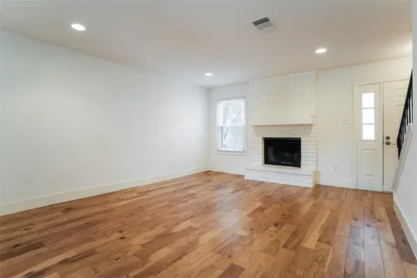 a view of empty room with wooden floor and fireplace